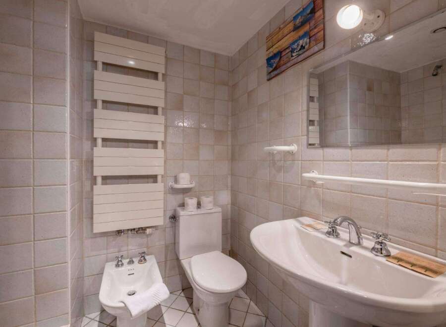 This charming bathroom features a classic design with tiled walls and a pedestal sink.