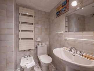 This charming bathroom features a classic design with tiled walls and a pedestal sink.