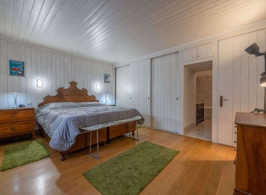 This charming bedroom features a cozy atmosphere with wooden floors and a unique wooden headboard.