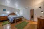 This charming bedroom features a cozy atmosphere with wooden floors and a unique wooden headboard.