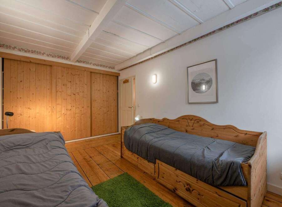 This charming bedroom features beautiful wooden accents, including a large sliding door closet and a pair of cozy beds.