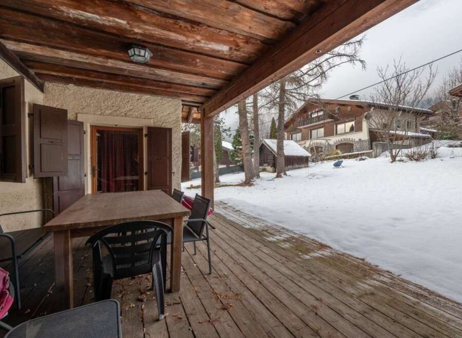 Enjoy the crisp mountain air from this charming covered porch, complete with a rustic wooden table and chairs, perfect for al fresco dining or morning coffee.
