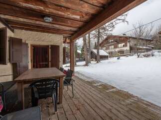 Enjoy the crisp mountain air from this charming covered porch, complete with a rustic wooden table and chairs, perfect for al fresco dining or morning coffee.