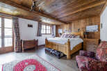 This charming bedroom boasts a rustic ambiance with its wooden ceiling and walls, creating a warm and inviting atmosphere.