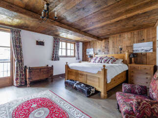 This charming bedroom boasts a rustic ambiance with its wooden ceiling and walls, creating a warm and inviting atmosphere.