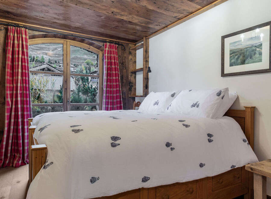 Experience the charm of this cozy bedroom featuring a rustic wooden ceiling and a comfortable bed.