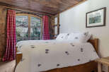 Experience the charm of this cozy bedroom featuring a rustic wooden ceiling and a comfortable bed.