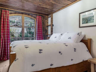 Experience the charm of this cozy bedroom featuring a rustic wooden ceiling and a comfortable bed.