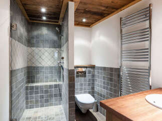 This stunning bathroom features a luxurious walk-in shower with elegant tile work and a wooden ceiling, creating a spa-like atmosphere.