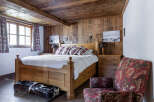 This cozy bedroom features a rustic wooden ceiling and walls, creating a warm and inviting atmosphere.