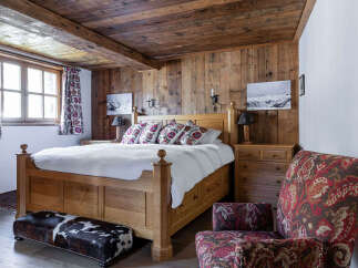 This cozy bedroom features a rustic wooden ceiling and walls, creating a warm and inviting atmosphere.