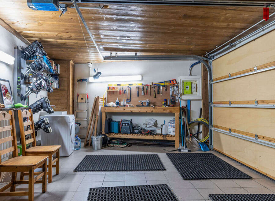 This garage offers ample space for storage and projects, featuring a workbench, tool organization, and a washing machine.