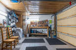 This garage offers ample space for storage and projects, featuring a workbench, tool organization, and a washing machine.