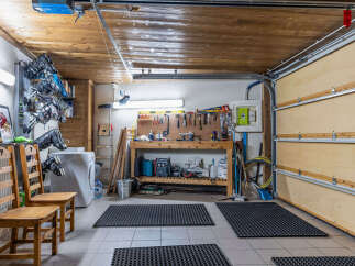 This garage offers ample space for storage and projects, featuring a workbench, tool organization, and a washing machine.