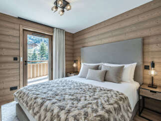 Experience luxurious mountain living in this beautifully appointed bedroom, featuring a plush king-size bed adorned with a cozy, fur-like throw.