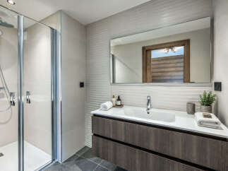 This modern bathroom features a sleek walk-in shower with chrome fixtures and a spacious vanity with a minimalist design.