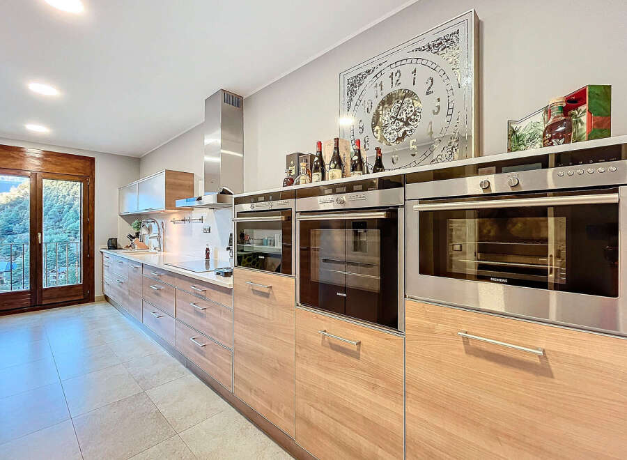 This modern kitchen boasts sleek, wooden cabinetry and state-of-the-art appliances, creating a stylish and functional space.
