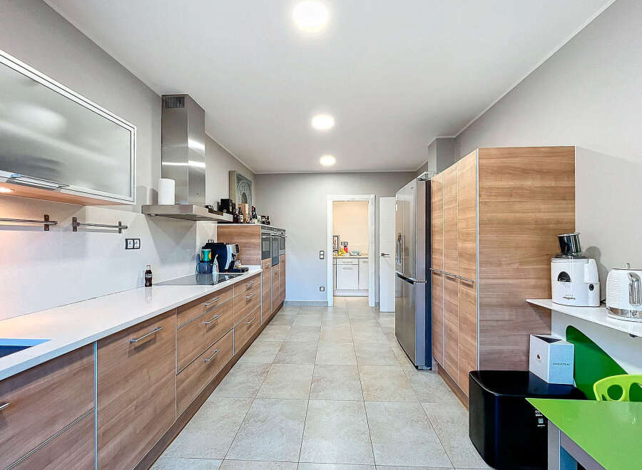 This modern kitchen boasts sleek wooden cabinetry and a pristine white countertop, creating a stylish and functional space.