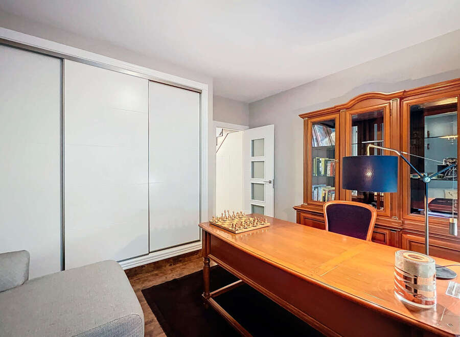 Discover the elegance of this well-appointed home office, featuring a classic wooden desk and a built-in bookcase.