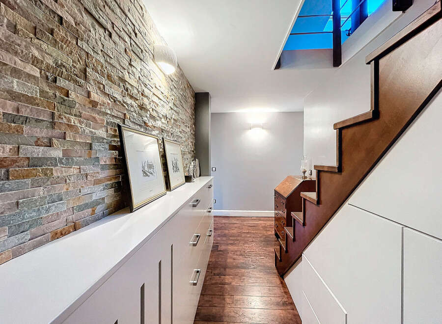 This stunning property features a beautifully designed hallway with a striking brick wall, creating a warm and inviting atmosphere.