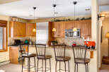 This stunning kitchen boasts beautiful wooden cabinetry, a stainless steel refrigerator, and a modern microwave.