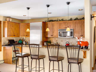 This stunning kitchen boasts beautiful wooden cabinetry, a stainless steel refrigerator, and a modern microwave.