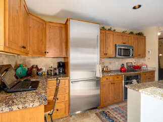 This stunning kitchen boasts beautiful wooden cabinetry and granite countertops, creating a warm and inviting atmosphere.