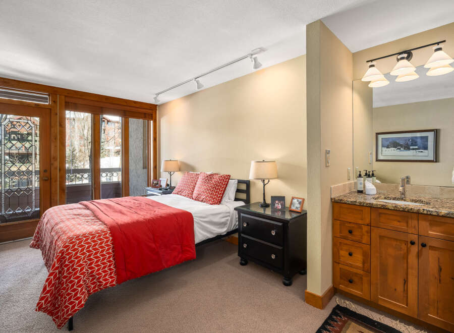 This stunning bedroom boasts a cozy ambiance with its inviting red bedding and stylish decor.