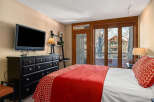 This cozy bedroom features a comfortable bed with a vibrant red comforter and a stylish accent pillow.