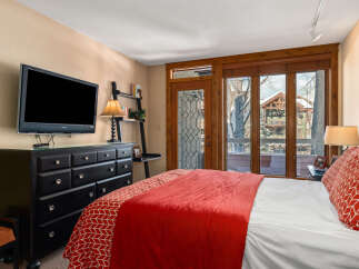 This cozy bedroom features a comfortable bed with a vibrant red comforter and a stylish accent pillow.