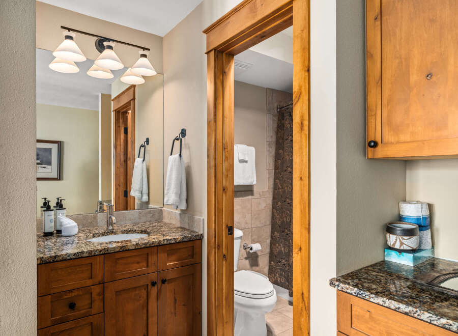 Step into this beautifully designed bathroom, featuring a warm wooden vanity and a stunning granite countertop.