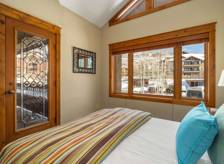 This cozy bedroom features a stunning view of the snowy landscape through large windows.