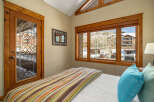 This cozy bedroom features a stunning view of the snowy landscape through large windows.