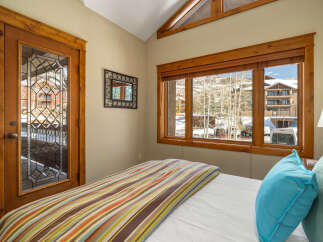 This cozy bedroom features a stunning view of the snowy landscape through large windows.