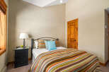 This cozy bedroom features a comfortable bed with a colorful striped comforter and accent pillows, creating a warm and inviting atmosphere.