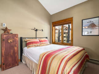 This cozy bedroom features a comfortable bed with a colorful striped comforter and pillows, creating a warm and inviting atmosphere.