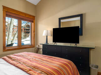 This cozy bedroom features a comfortable bed with a vibrant striped comforter, perfect for a relaxing stay.