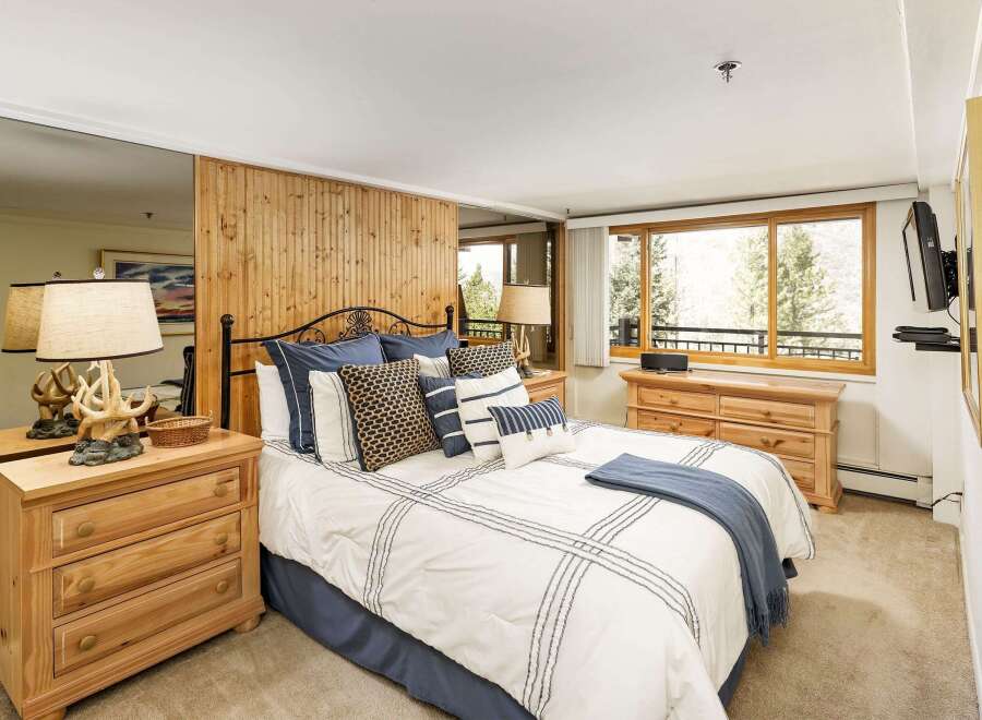 This inviting bedroom features a cozy ambiance with its warm wooden accents and plush bedding.
