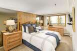 This inviting bedroom features a cozy ambiance with its warm wooden accents and plush bedding.