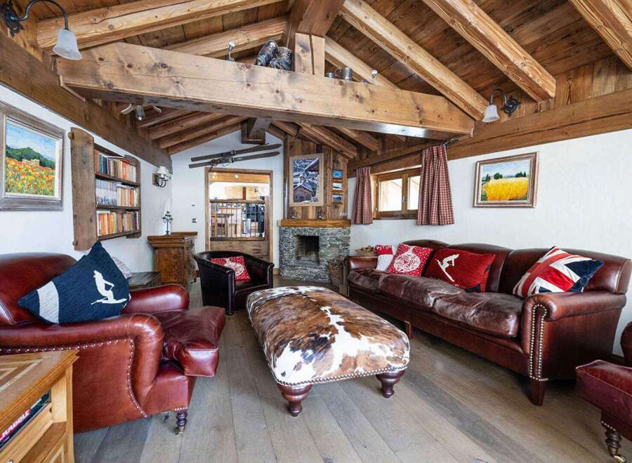Step into luxury with this stunning property, boasting a cozy living room with a rustic wooden ceiling and a stone fireplace.