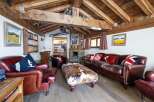 Step into luxury with this stunning property, boasting a cozy living room with a rustic wooden ceiling and a stone fireplace.