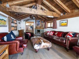 Step into luxury with this stunning property, boasting a cozy living room with a rustic wooden ceiling and a stone fireplace.