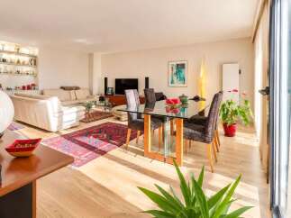 Experience modern living in this spacious open-plan apartment, featuring a bright living area with plush sofas and a stylish dining space with a glass-top table.