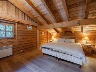 Step into rustic charm with this cozy bedroom featuring warm wooden walls and a vaulted ceiling.