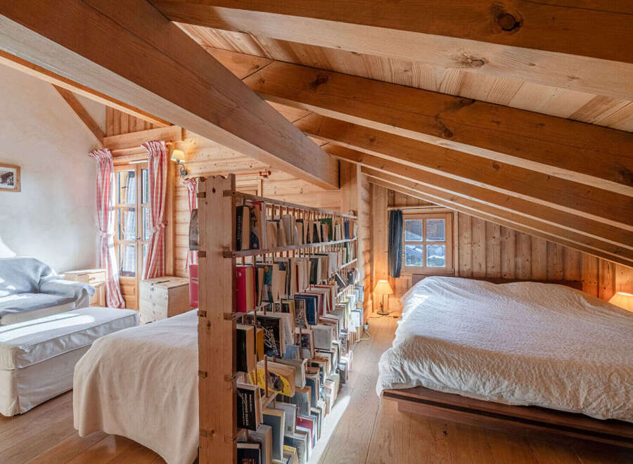 Discover the charm of this cozy attic bedroom, featuring a unique wooden bookshelf that adds character and functionality.