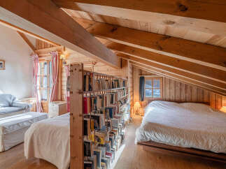 Discover the charm of this cozy attic bedroom, featuring a unique wooden bookshelf that adds character and functionality.