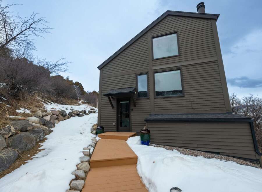 This stunning property boasts a modern design with a unique sloped roof and large windows, offering breathtaking views.