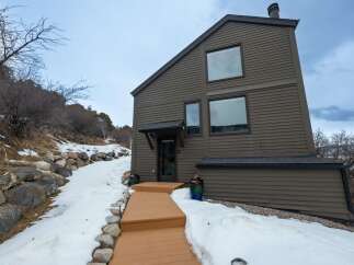 This stunning property boasts a modern design with a unique sloped roof and large windows, offering breathtaking views.