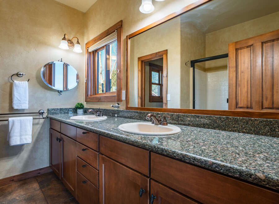 This stunning bathroom features a double vanity with a granite countertop, offering ample space and a touch of luxury.