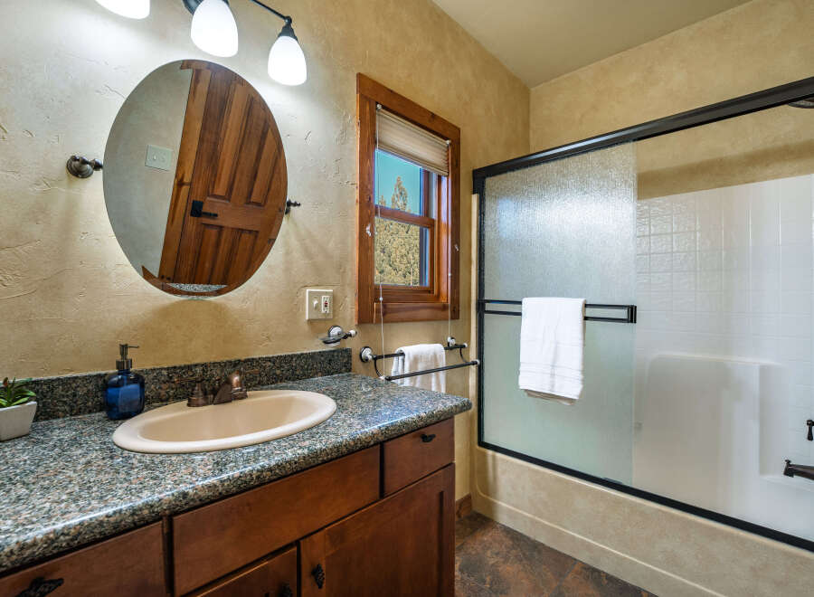 This charming bathroom features a rustic design with a wooden vanity and a granite countertop.